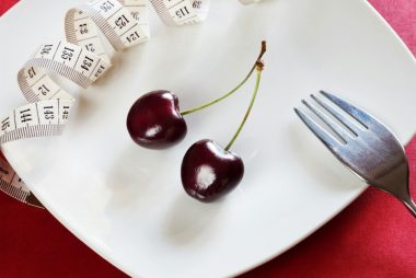 Diet white plate with centimeter, cherry, fork